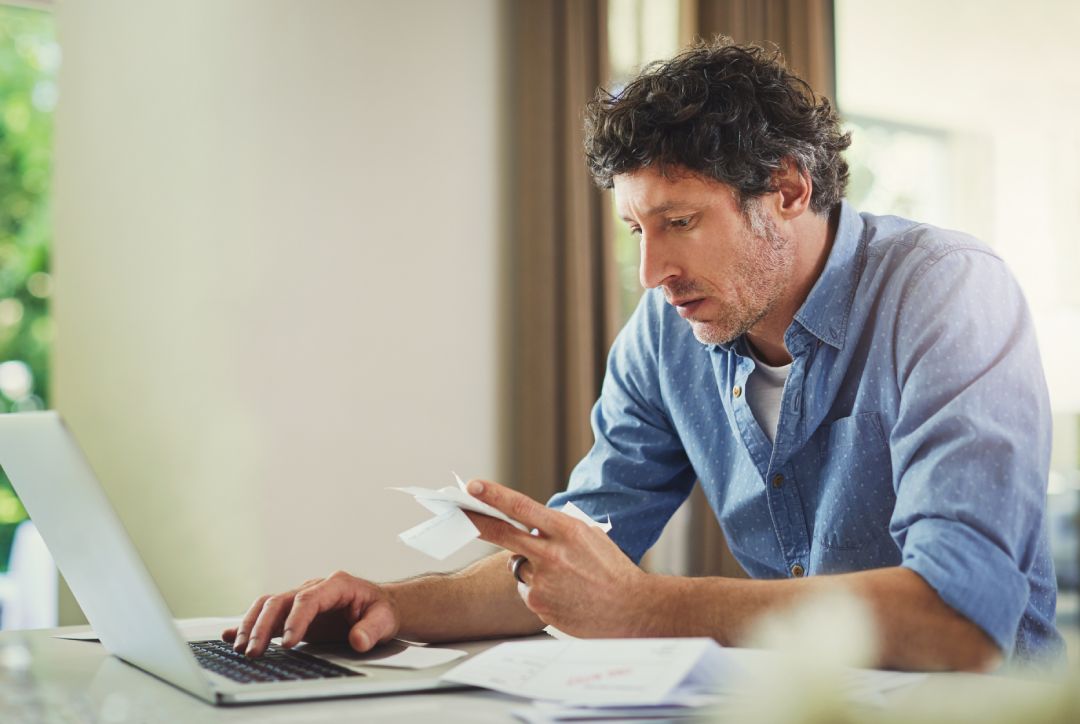 Mann sitzt an seinem Laptop und legt mit Robo-Advisors Geld online an